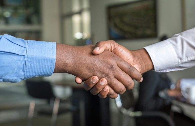 Handschlag zweier Personen am Besprechungstisch